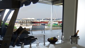 A bathtub filled with bubbles, a bench, a window with a view of boats, and a champagne bottle. - Atakoy Marina Park Hotel Residences (Istanbul)