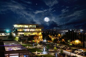 A modern hotel with a glass facade, a parking lot, and a view of the moon. - Atakoy Marina Park Hotel Residences (Istanbul)