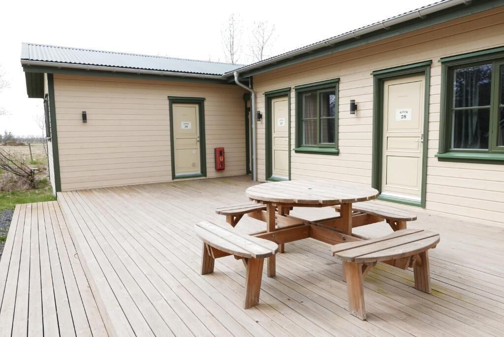 A wooden deck with a picnic table and benches, a building with green trim and numbered doors, and a fire hydrant.
