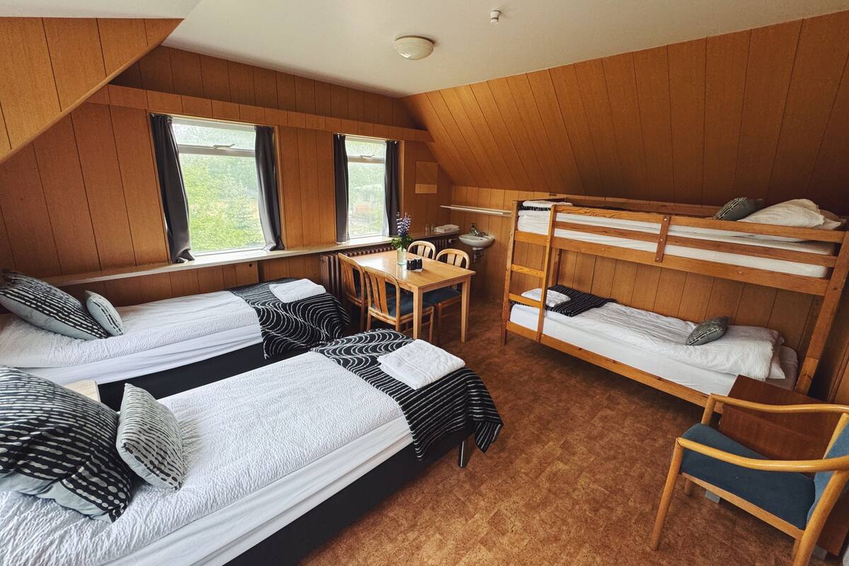 Une chambre de dortoir avec des lits superposés, un bureau, une chaise et une fenêtre.
