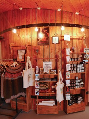A wooden interior with a display of sweaters, bags, and jars of honey.