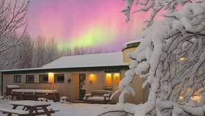 Een gebouw bedekt met sneeuw, met een zichtbaar terras buiten en uitzicht op het noorderlicht.