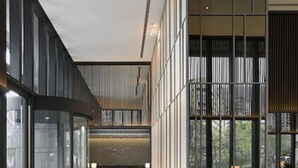 Een moderne hotel lobby met een gebogen glazen wand, een receptiebalie en uitzicht op de omgeving.