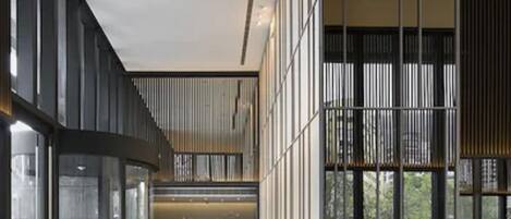A modern hotel lobby with a curved glass wall, a reception desk, and a view of the outdoors.