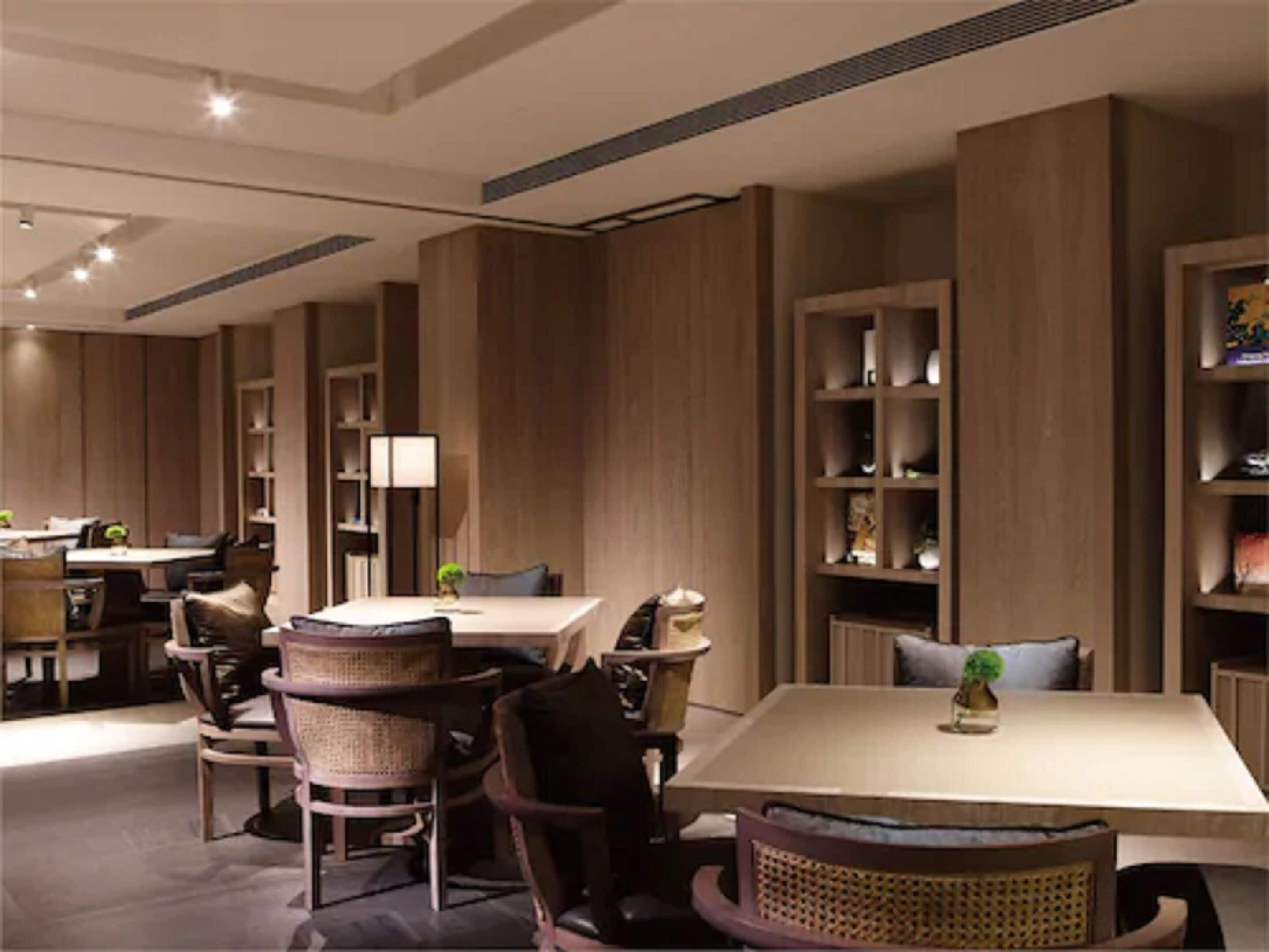 Een moderne eetruimte met hoge houten wanden, een centrale tafel en rieten stoelen.