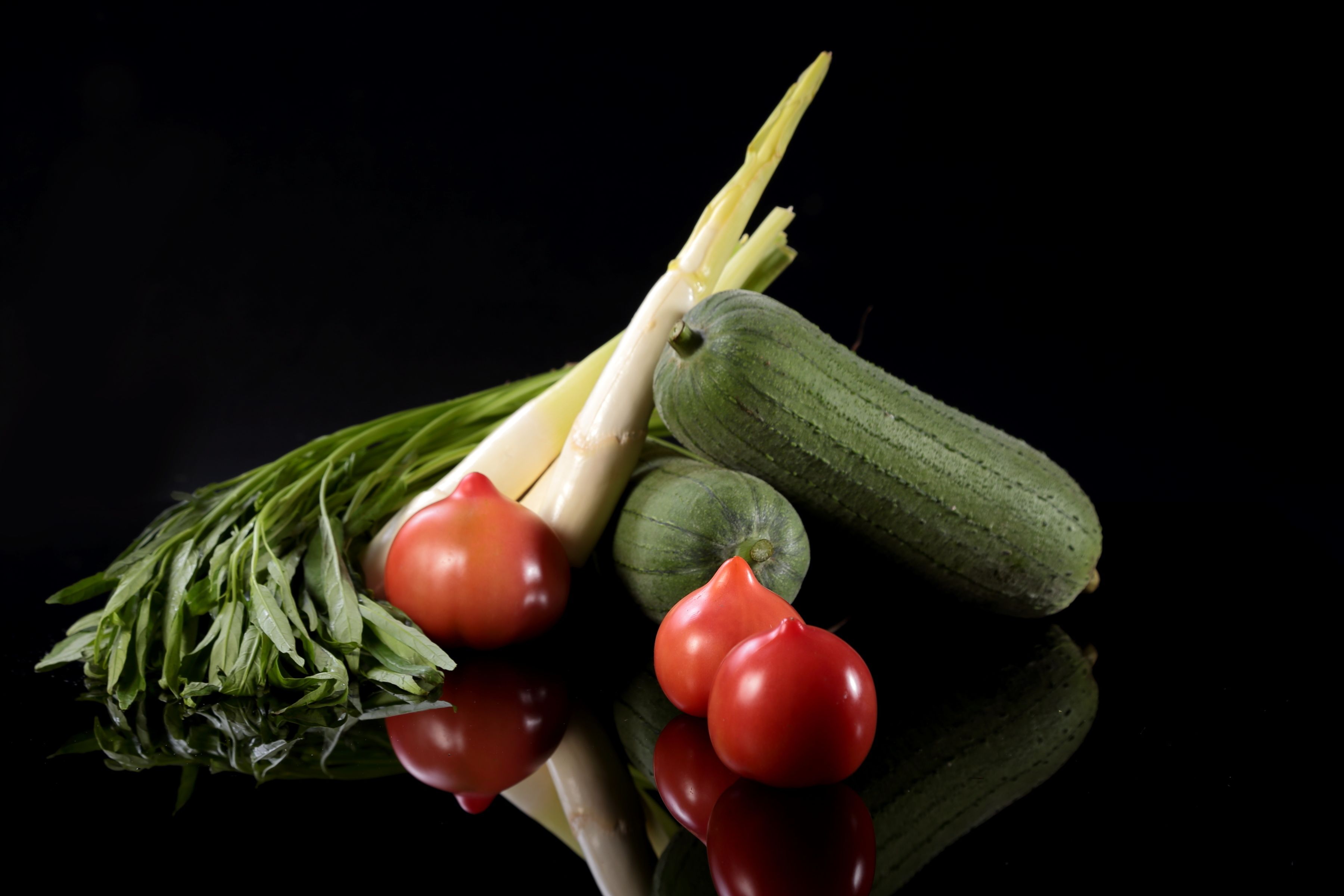 A selection of fresh vegetables including tomatoes, zucchini, and leafy greens.
