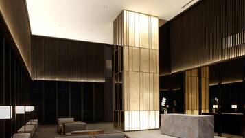 A modern lobby with seating areas, a reception desk, and a large illuminated wall.