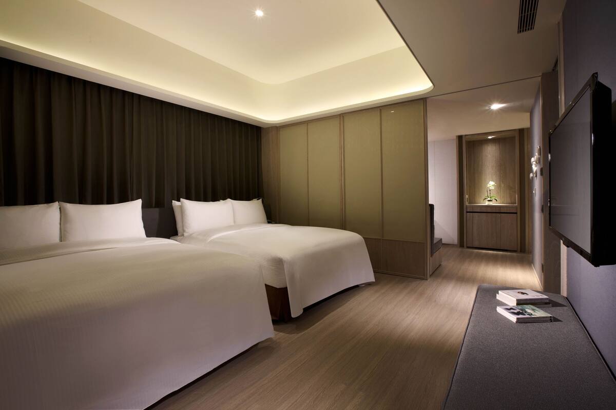 Ett modernt hotellrum med två sängar, en platt-TV och en liten sittgrupp.