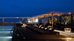 A poolside area with lounge chairs and umbrellas, overlooking a body of water at night. - Wellspring by Silks Jiao Xi (Jiaoxi)
