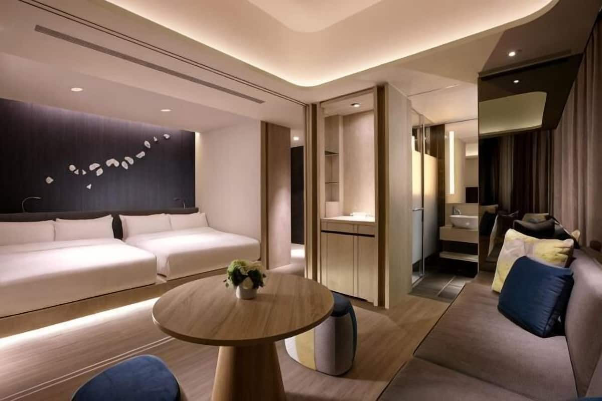 Ett modernt hotellrum med en soffa, ett runt bord, en liten växt och en spegel.