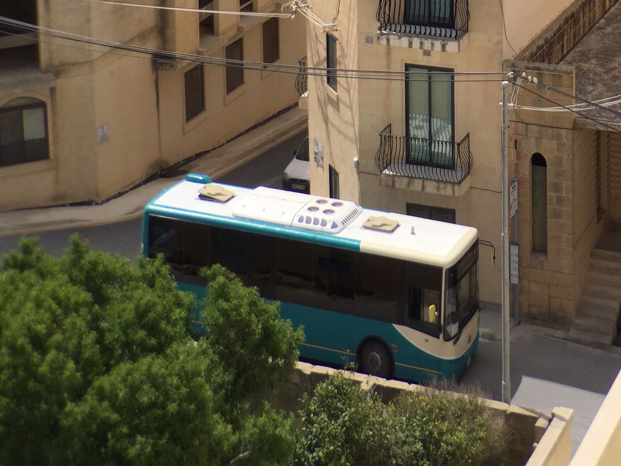 A bus parked in an urban area with buildings and a staircase in the background.