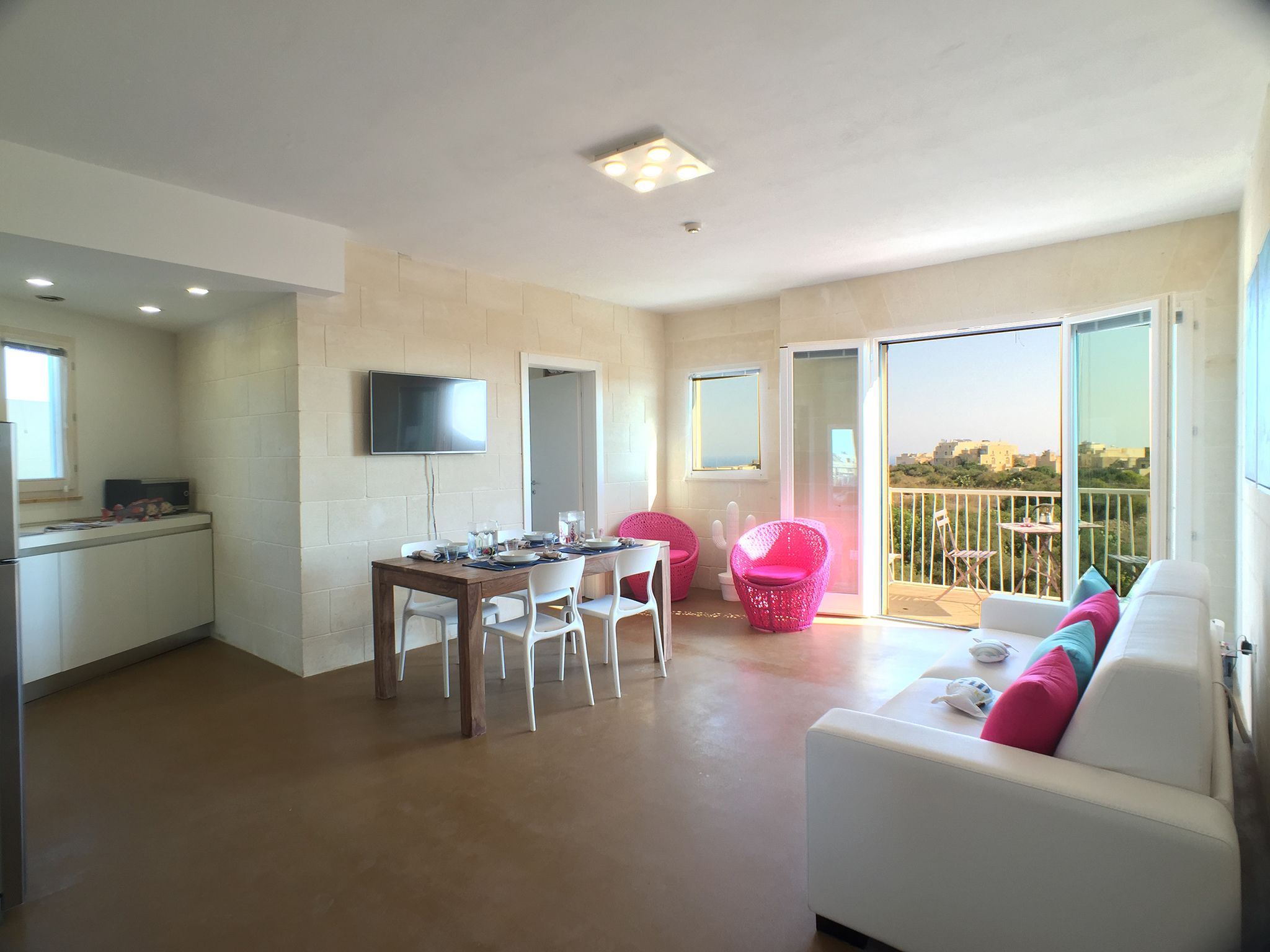 Een modern appartement met een eethoek, een woonkamer met een bank, een balkon met uitzicht en een keuken.