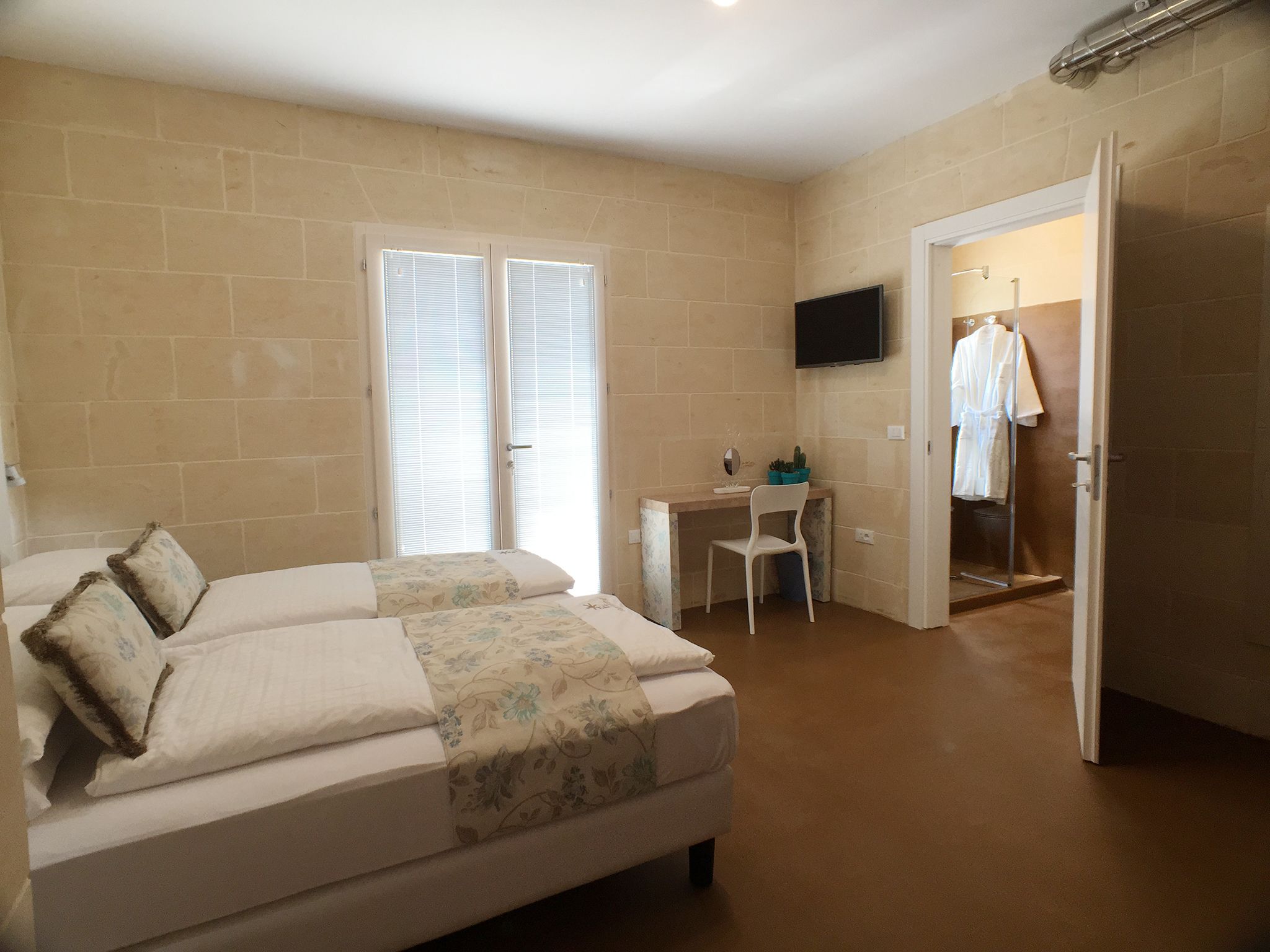 Un dormitorio con cama, escritorio y televisor.