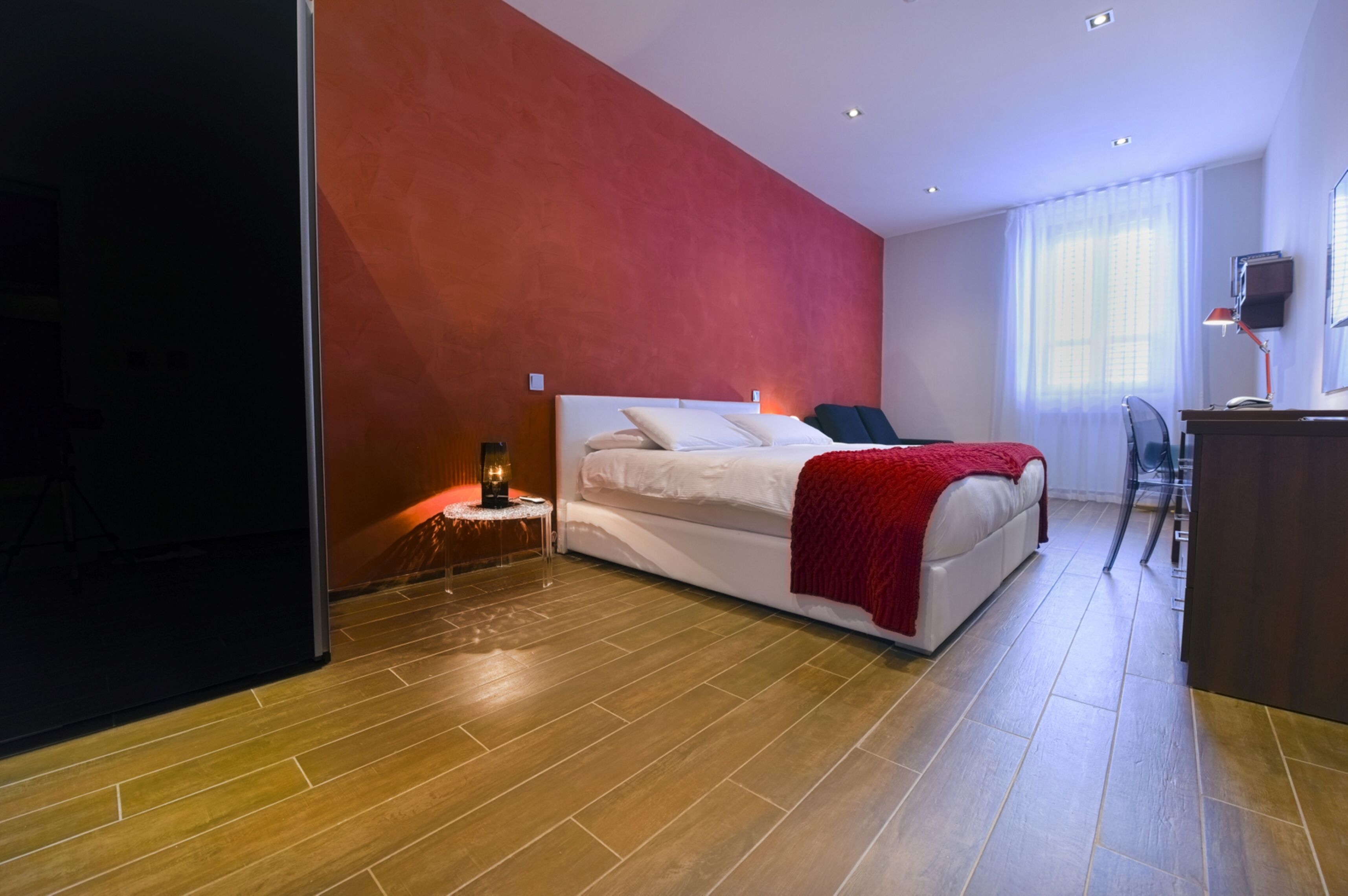A modern hotel room with a large bed, a desk, and a chair.