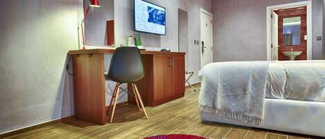 Ein modernes Hotelzimmer mit einem Holztisch, einem großen Bett, einem an der Wand befestigten Fernseher und einem roten Teppich.