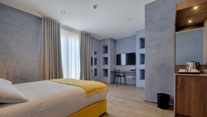 Una habitación de hotel moderna con una cama grande, un escritorio y una televisión.