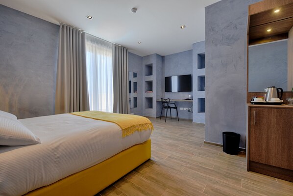 Una habitación de hotel moderna con una cama grande, un escritorio y una televisión.