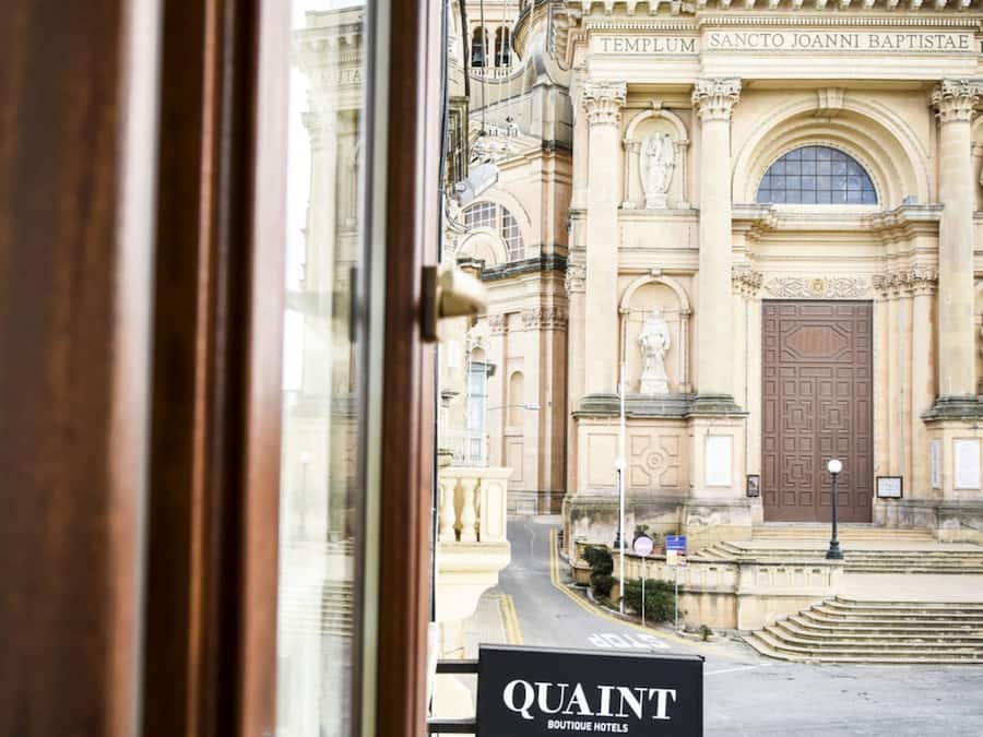 Vista de un edificio histórico con una cúpula grande y arquitectura ornamentada, visible desde la entrada de un hotel.