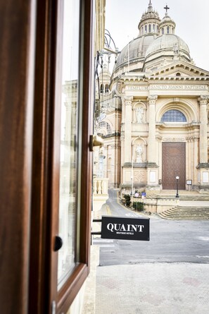 A view of a historic building with a large dome and ornate architecture, viewed through a hotel entrance. - Quaint Boutique Hotel Xewkija (Xewkija)