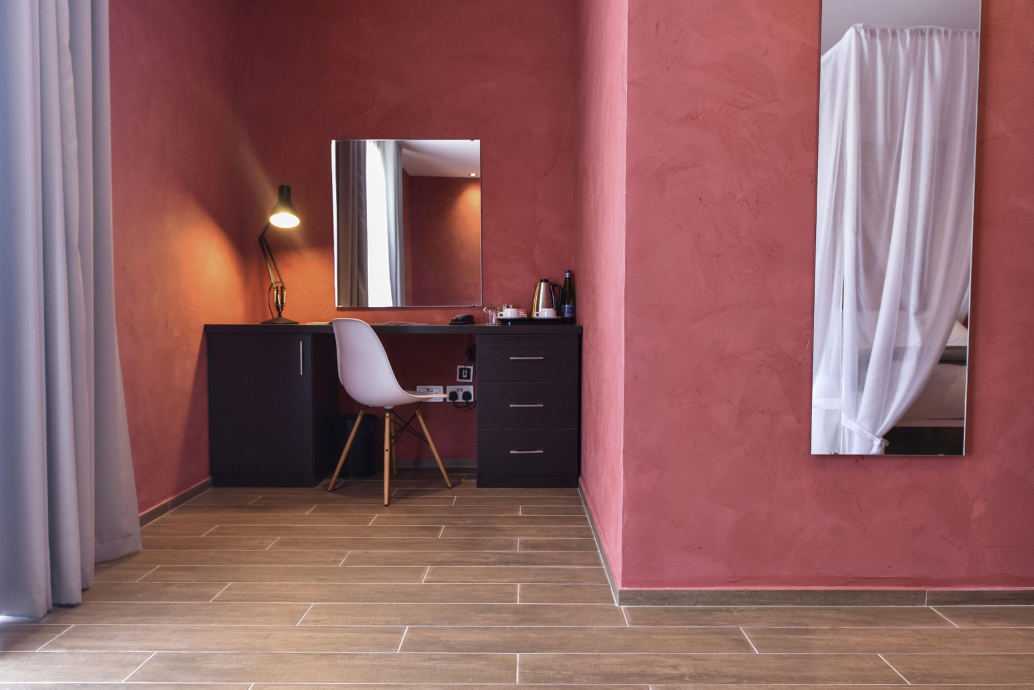 A room with a desk, chair, and a mirror.