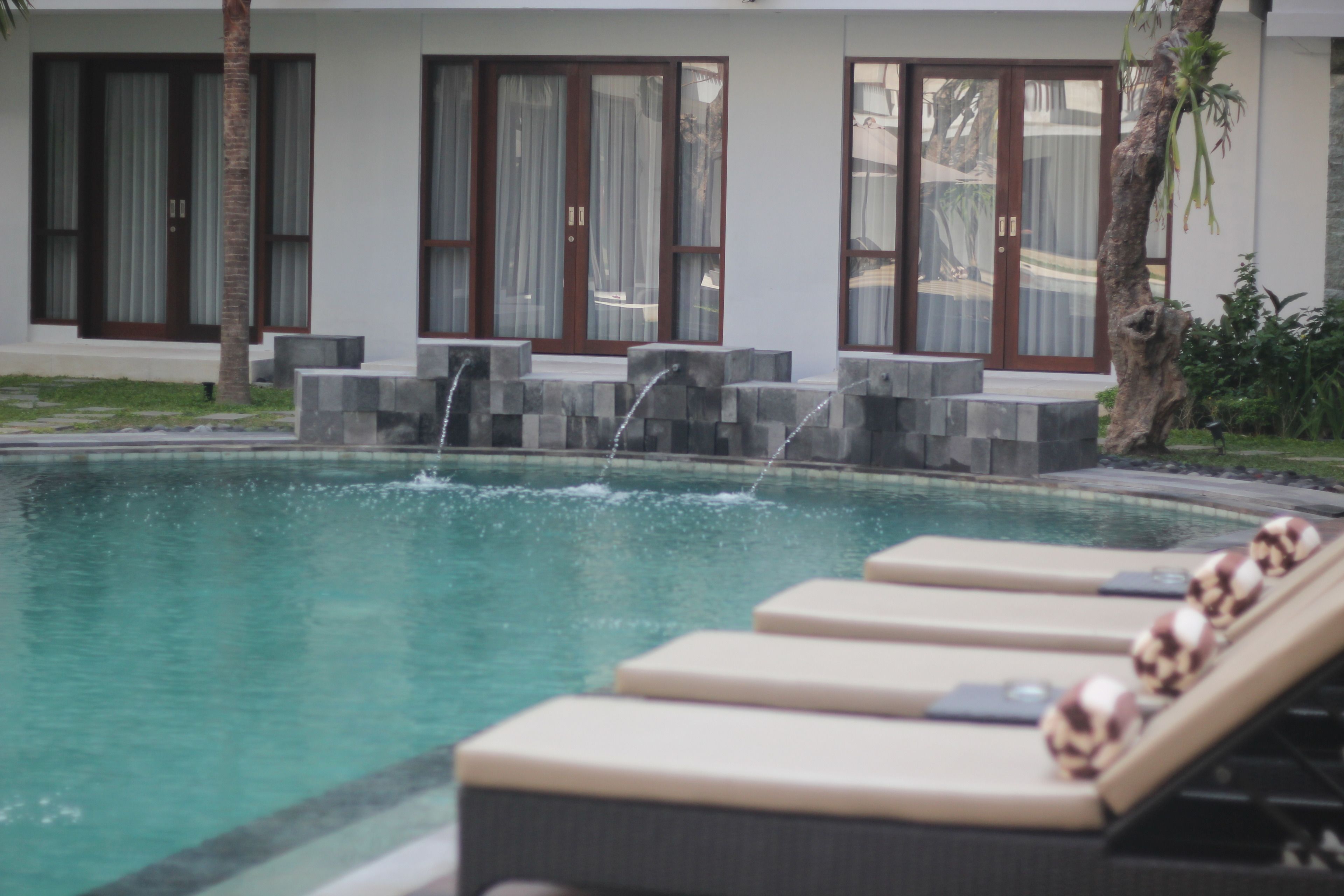 A swimming pool with lounge chairs and a water feature.