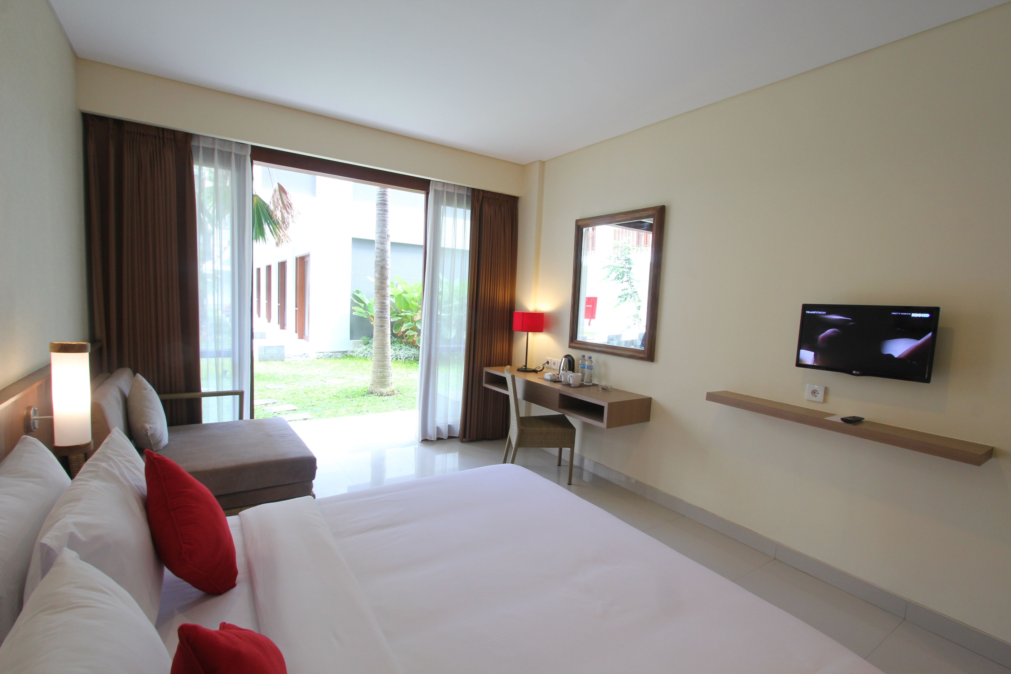 Habitación de hotel con una cama grande, escritorio, televisor y vistas al exterior.