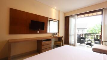 Ein Hotelzimmer mit Bett, Schreibtisch, Stuhl, Fernseher und einem Balkon mit Sitzgelegenheiten.