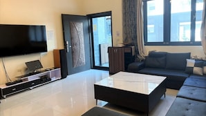 A modern living room with a flat-screen TV, a coffee table, a sofa, and a cabinet. - Kenting MuChen INN (Hengchun)