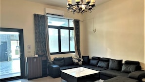 A modern living room with a sectional sofa, a glass coffee table, and a chandelier. - Kenting MuChen INN (Hengchun)