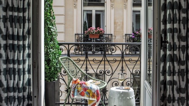 A balcony with a chair, a potted plant, and a decorative vase. - Hôtel Adèle & Jules (Paris)