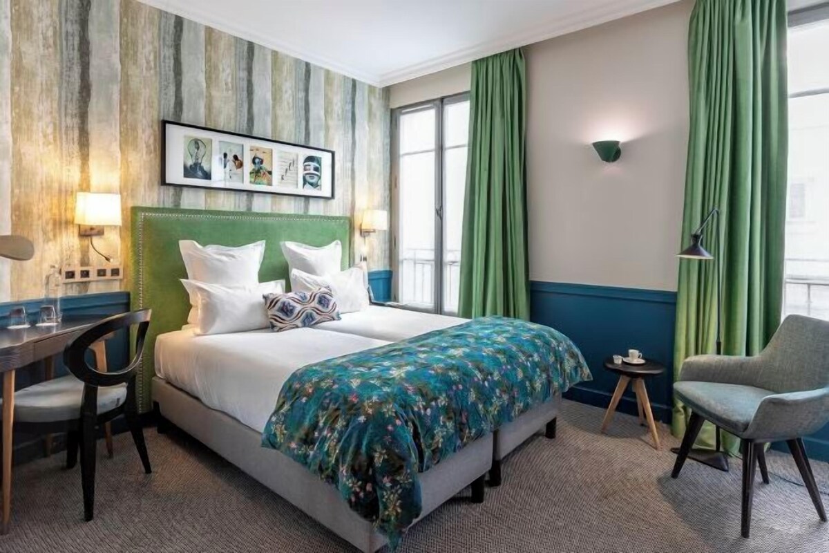 Et hotelværelse med en seng, et skrivebord, en stol og et lille bord.