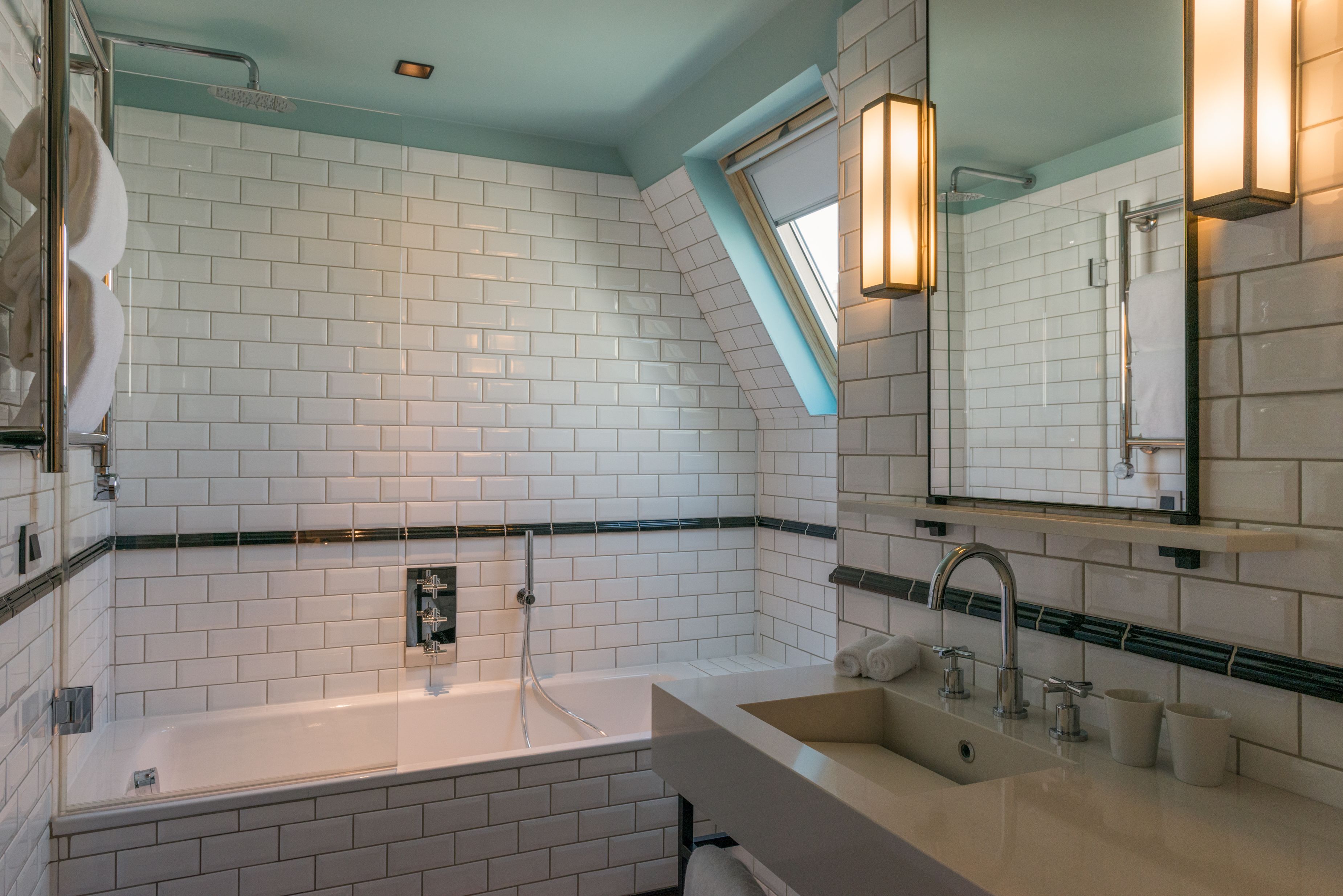 Een moderne badkamer met witte metrotegels, een badkuip, een wastafel en een grote spiegel.