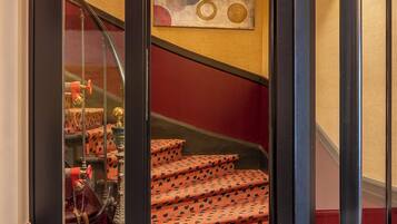 Uma escada com carpete estampado e parede vermelha.