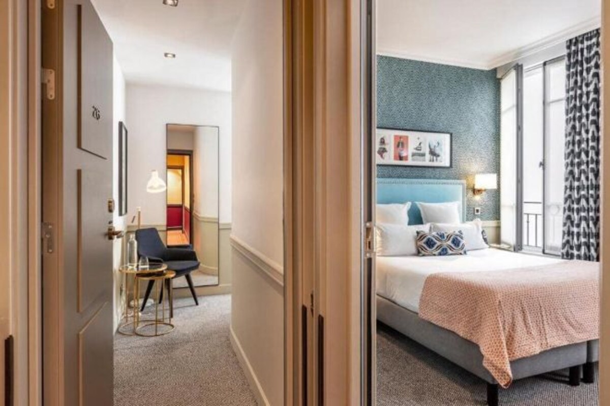 Una habitación de hotel con cama, escritorio, silla y vistas al exterior.