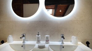 A bathroom with two sinks, each with a mirror above. There are two soap dispensers and a towel dispenser on the counter.