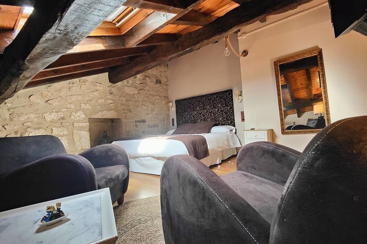 A cozy room with a stone wall, a bed, and two sofas.