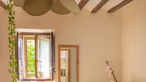 A room with a wooden ceiling, a white sofa, a small round table, and a window with a view of greenery outside. - Casa Rural La Molinera Etxea (Samaniego)