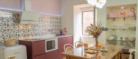 A kitchen with a central island, a refrigerator, and a dining table with chairs.