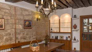 A rustic interior with a stone wall, wooden bench, and a chandelier. - Casa Rural La Molinera Etxea (Samaniego)