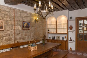 Um interior rústico com parede de pedra, banco de madeira e um candelabro.