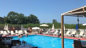 A pool area with lounge chairs and umbrellas, surrounded by a wooden deck and a white fence. - Velena Hotel (Sile)