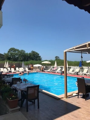 Una piscina al aire libre, sombrillas, sillones reclinables de piscina
