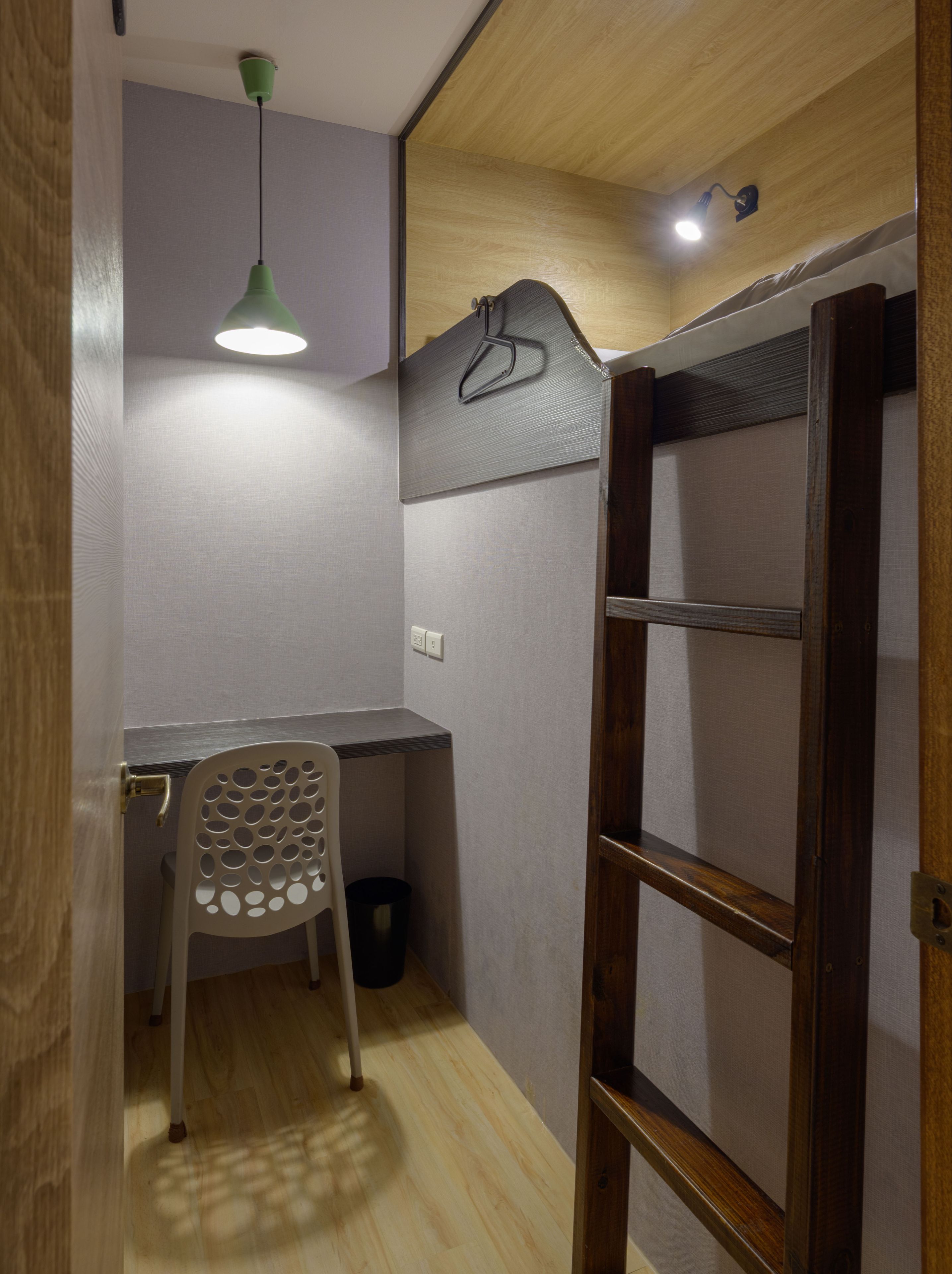 A compact room with a desk, chair, and ladder.