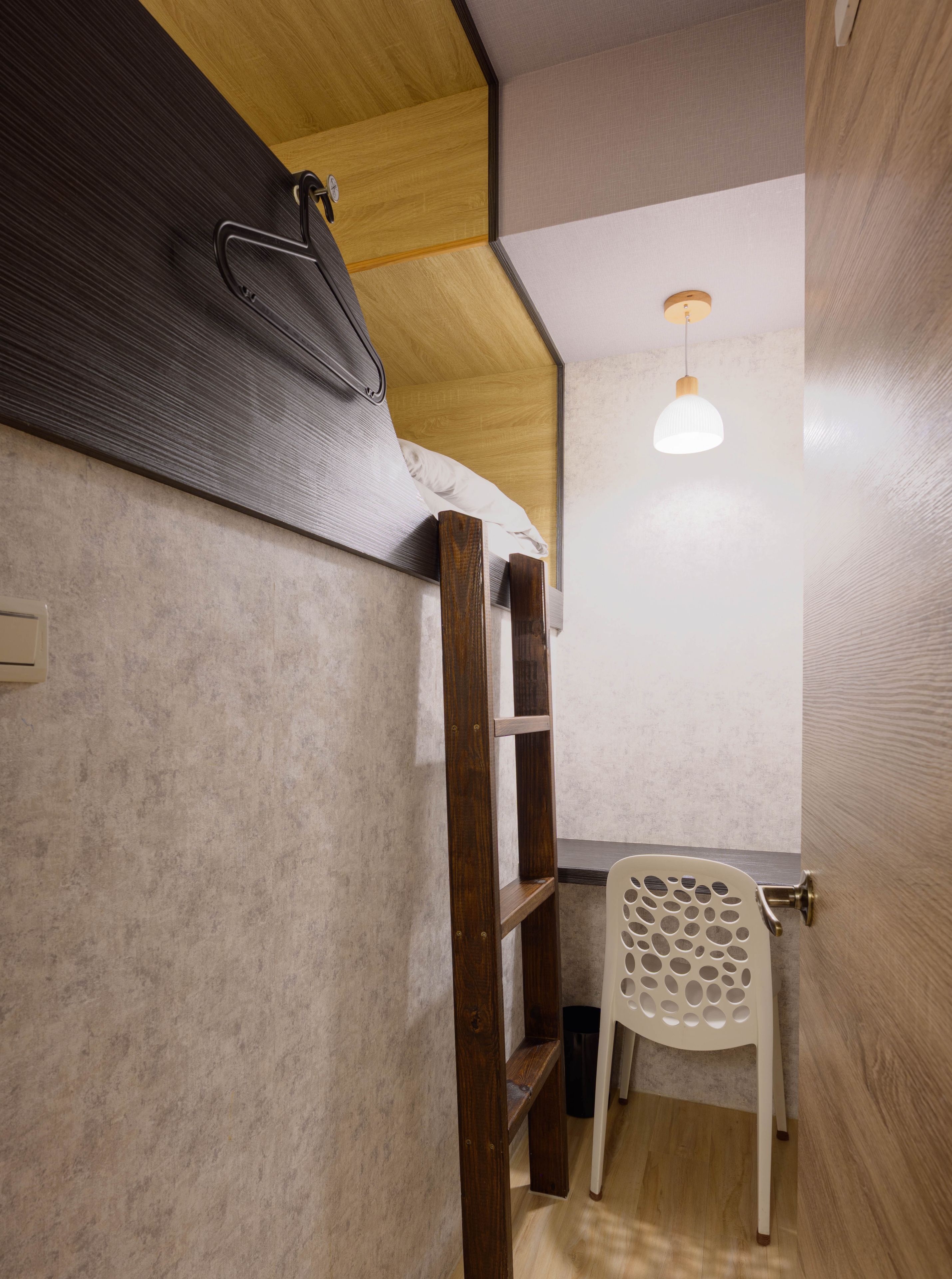 Une pièce de taille modeste avec un plafond en bois, une chaise blanche et une petite étagère.
