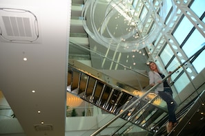 Um interior moderno com um poço de elevador de vidro, uma escadaria em espiral e um lustre decorativo.