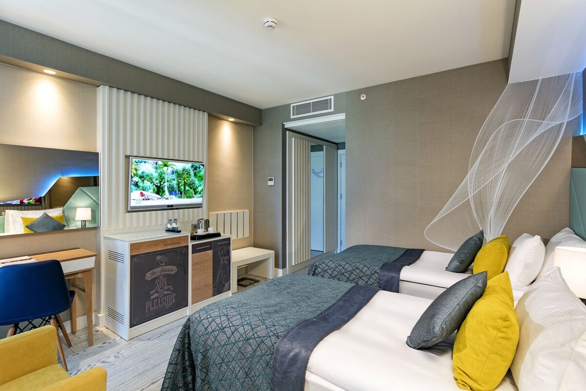 A hotel room with a bed, a desk, a television, and a bathroom door.