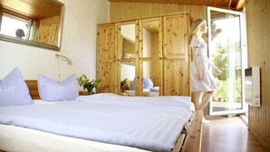 Une chambre à coucher comprenant un lit, une armoire en bois et une porte-fenêtre coulissante donnant sur un balcon.