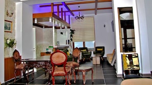 A spacious living area with a dining table, multiple chairs, a sofa, and a staircase leading to an upper level. - Fly Inn Brussels Airport (Machelen)
