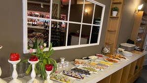 A buffet setup with various food items and a wine rack in the background. - Fly Inn Brussels Airport (Machelen)