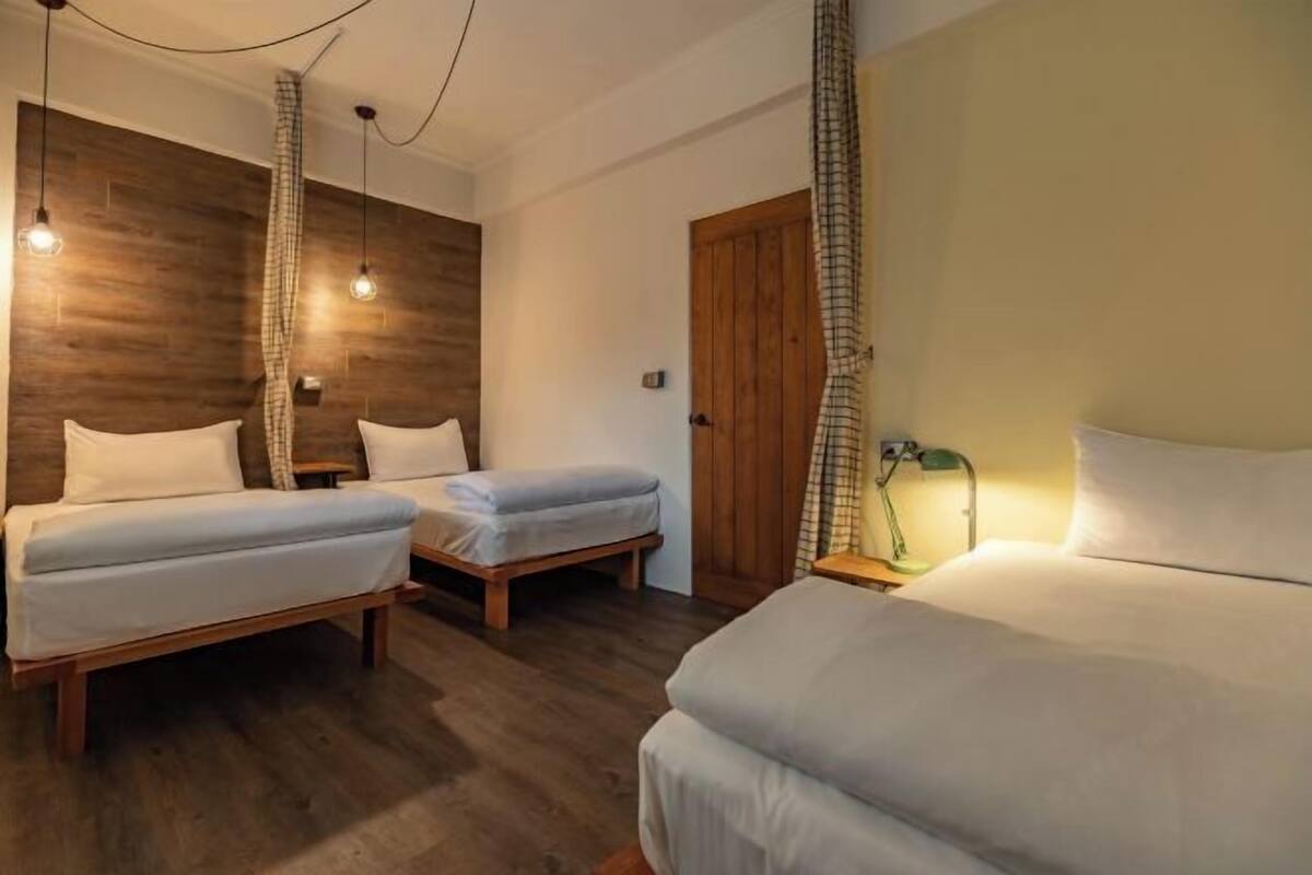 Een hotelkamer met twee enkele bedden, een houten accentmuur en een groot bed.